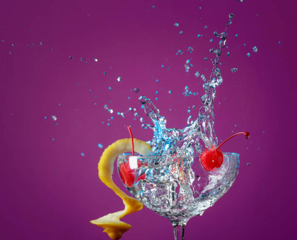 istock Ccktail in glass with splashes garnished with lemon and cherries. 1177843893
