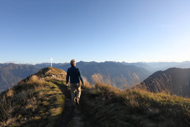 He looks off to distant scene, with religious cross behind