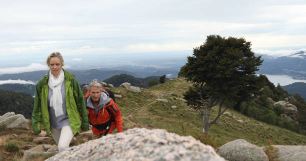 istock Couple hike up grassy mountain ridge 1177846477