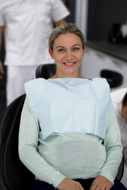 Beautiful pregnant woman at a late date in a black dental chair stock photo