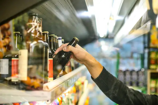 Unrecognizable man buying beer in a supermarket store.