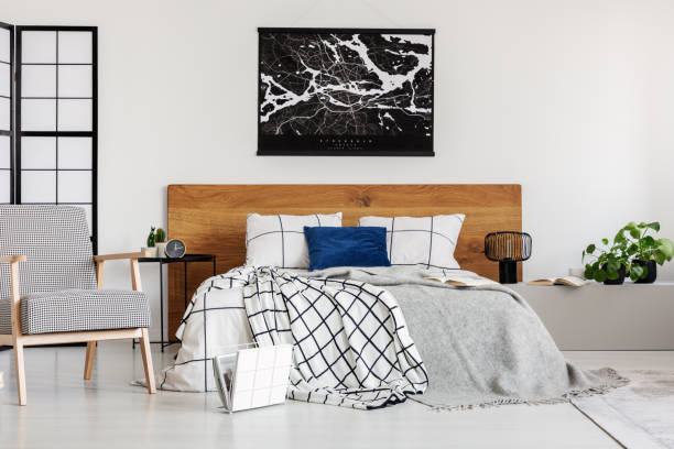 istock Black map on white wall above wooden headboard in simple bedroom interior 1177849694
