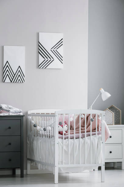 istock White crib with paste pink bedding and cotton balls in bright bedroom interior 1177851150