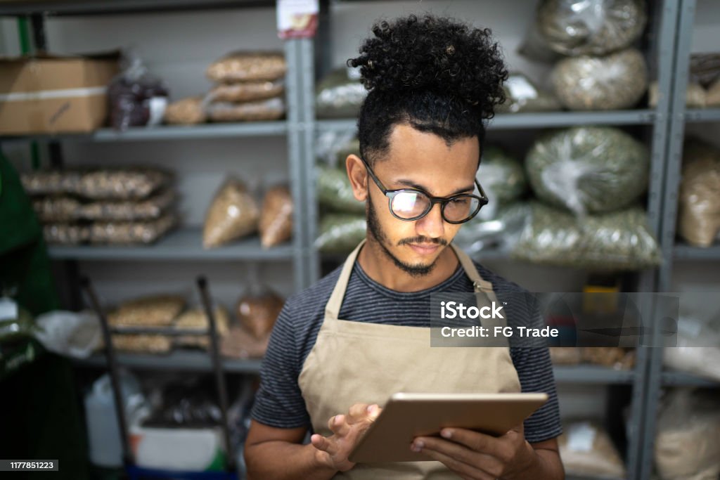 Men using digital tablet in storage room of a natural product shop Retail Stock Photo