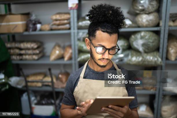 Men Using Digital Tablet In Storage Room Of A Natural Product Shop Stock Photo - Download Image Now