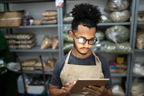 Photo of Men using digital tablet in storage room of a natural product shop