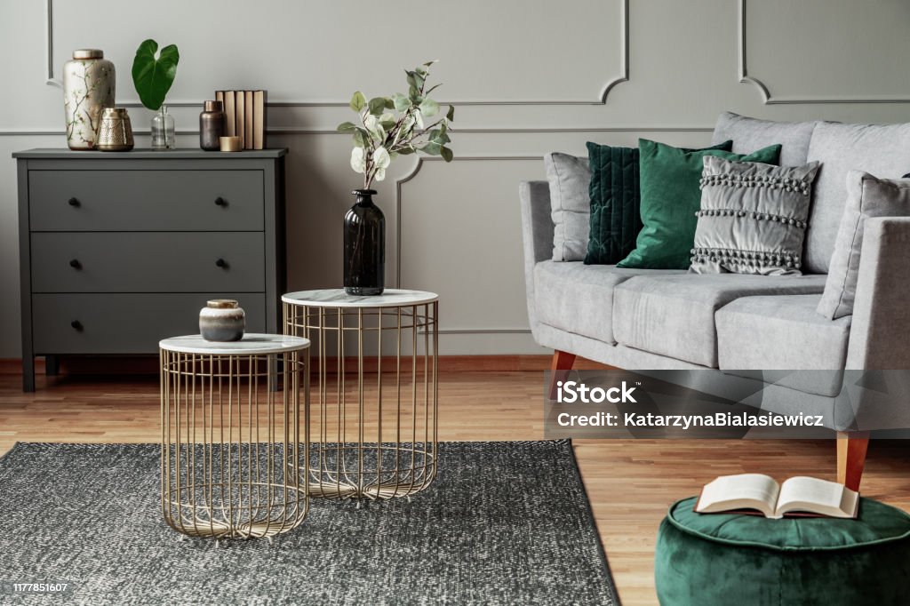 Two stylish small coffee tables with marble tops in front of elegant grey couch with emerald pillows Living Room Stock Photo