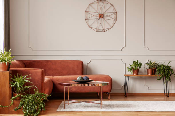 istock Brown comfortable corner sofa in elegant living room interior with grey wall with molding and fancy clock 1177851730