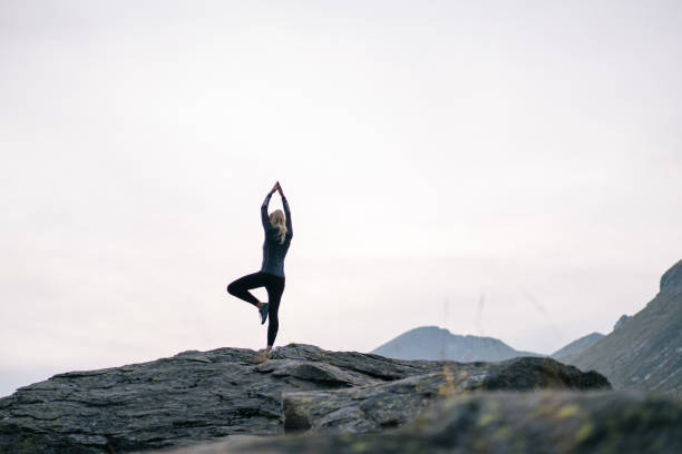 istock Woman performs yoga moves on rock in mountains 1177852995