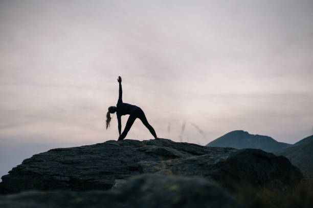 istock Woman performs yoga moves on rock in mountains 1177853072