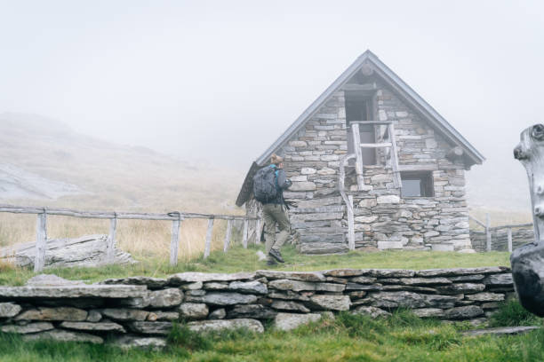 istock Hiker arrives at stone cabin in mist 1177853886