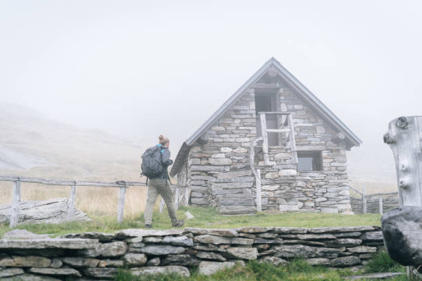 istock Hiker arrives at stone cabin in mist 1177853901
