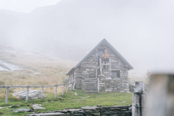 istock Hiker stands on stone cabin steps in mountain meadow 1177854140