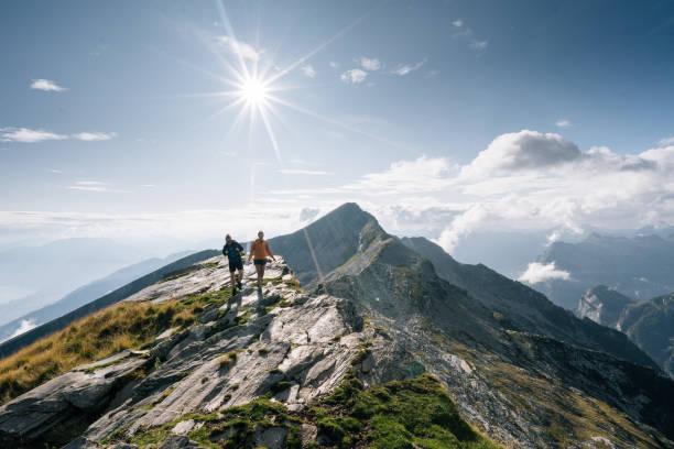 Couple hike along a mountain ridge in the bright sun