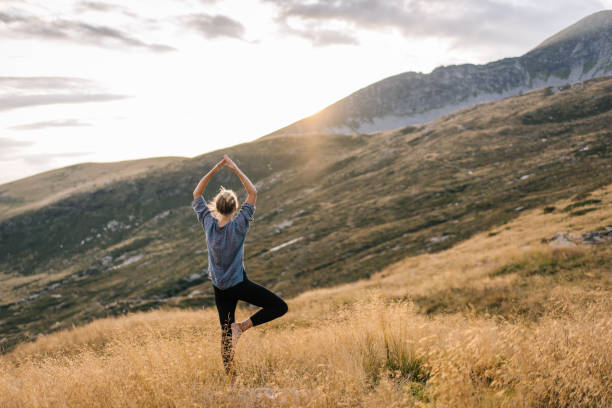 giovane donna preforma lo yoga in montagna alla luce del mattino - spirituality yoga zen like meditating foto e immagini stock