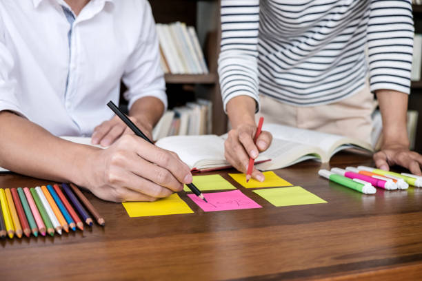 istock High school or college student group sitting at desk in library studying and reading, doing homework and lesson practice preparing exam to entrance, education concept 1177860826