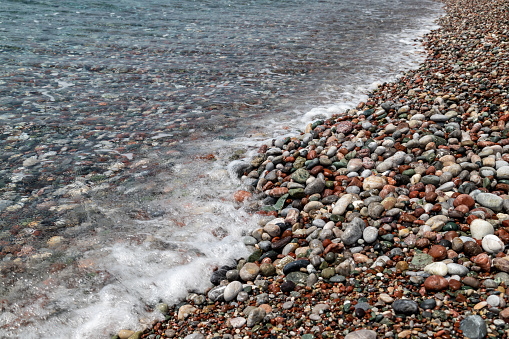 Beach panorama with pebbles on the shore on a sunny day - Long exposure