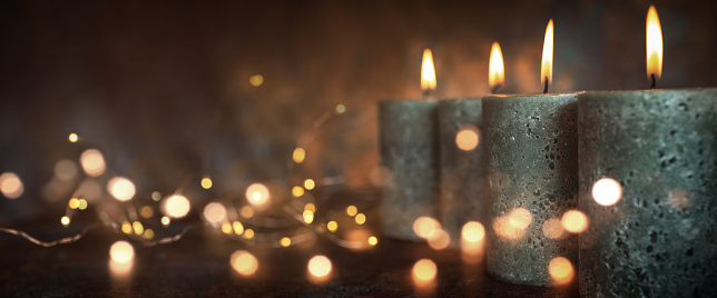 Candles with festive lights in front of dark background