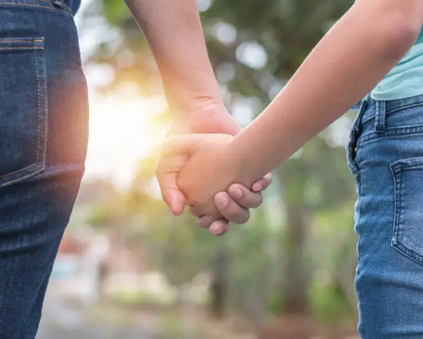 Photo of Mother and child teenager girl daughter holding hands for family care support, parenting, teen child safety assurance awareness concept