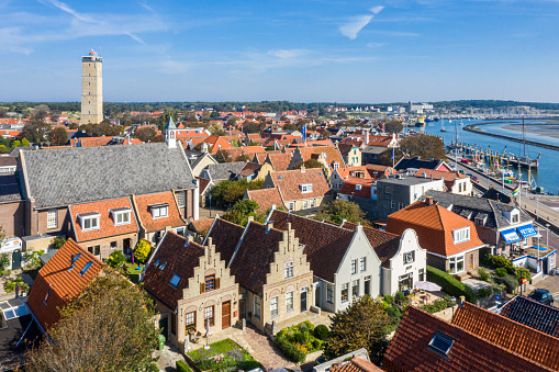 Netherlands, Terschelling - Aug 25, 2019: Brandaris lighthouse and Westerkerk, harbour and historical houses of West-Terschelling town. Shallow waters, sandy banks in low tide. West Frisian Islands.