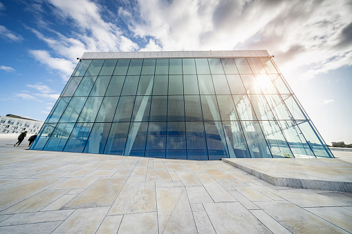 Oslo, Norway - September 15, 2019: Glass cube of the fururistic modern architecture Opera House - Operahuset - of Oslo. Modern Glass Facade under blue sunny late summer skyscape. Oslo, Norway, Scandinavia, Europe.