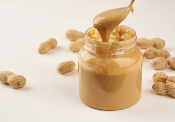 Crunchy peanut butter served on a spoon, isolated on a white background.