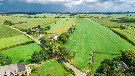 Aerial drone view of green fields and farm houses near canal from above, typical Dutch landscape, Holland, Netherlands