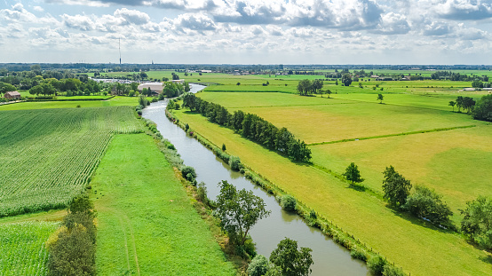 Aerial drone view of green fields and farm houses near canal from above, typical Dutch landscape, Holland, Netherlands