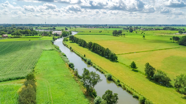 aerial drone view of green fields and farm houses near canal from above, typical dutch landscape, holland, netherlands - polder field meadow landscape imagens e fotografias de stock