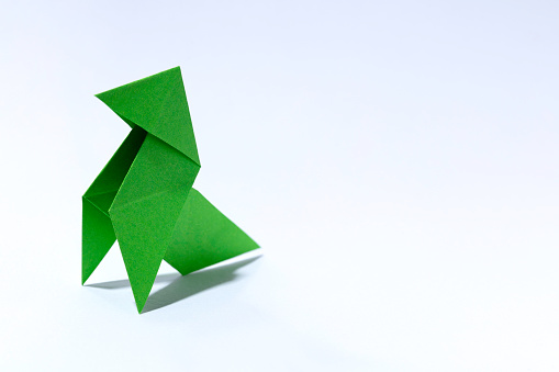classic green paper bird origami with free space for text on the right side, high cartoon texture and big size