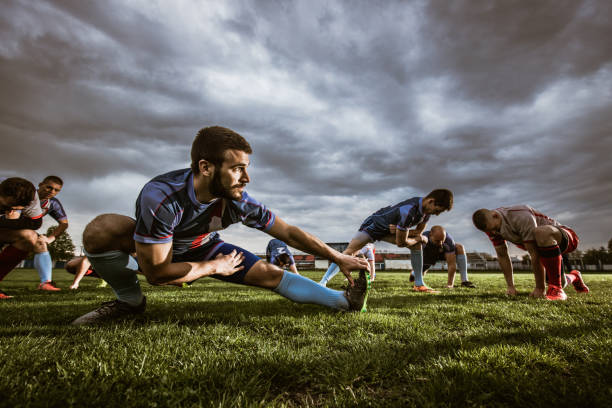 grupo de deportistas haciendo ejercicios de estiramiento en un estadio. - rugby soccer grass playing field fotografías e imágenes de stock