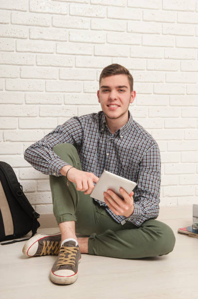 istock Young man sits with textbooks on the floor 1177894176