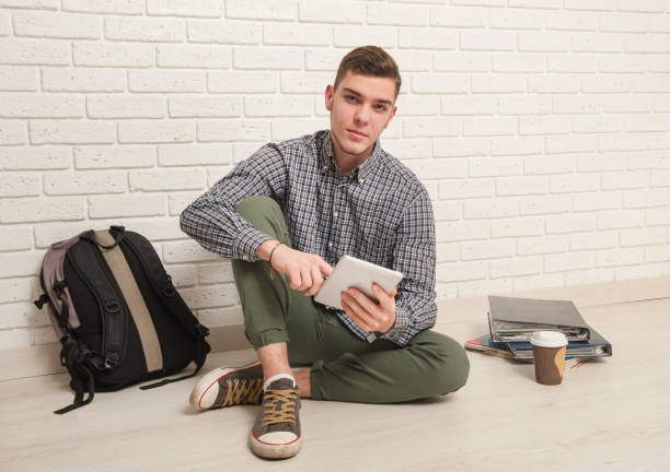 istock Young man sits with textbooks on the floor 1177894183