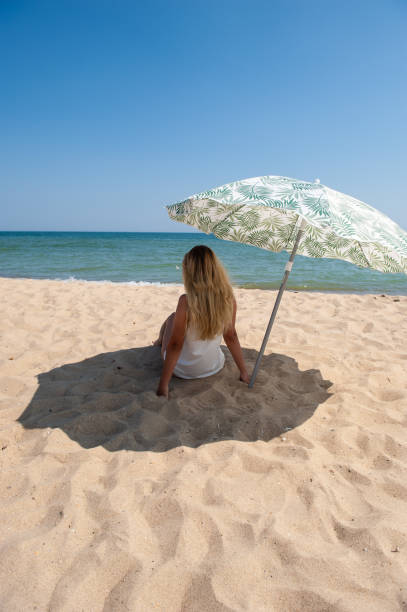 istock Girl sitting under a beach umbrella 1177894375