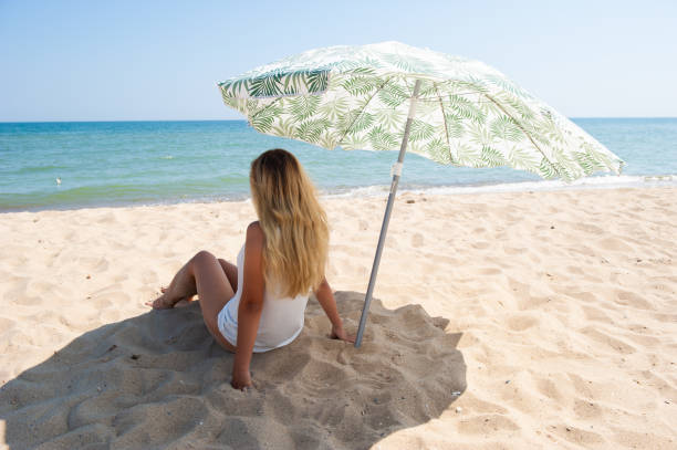 istock Girl sitting under a beach umbrella 1177894387