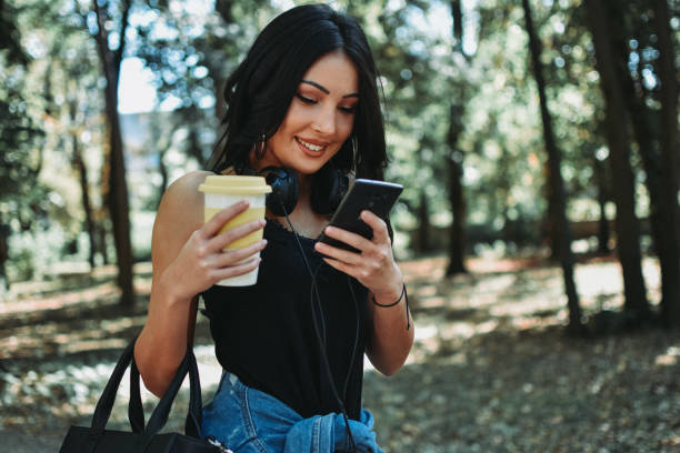 istock Woman texting and drinking coffee in the park 1177895551