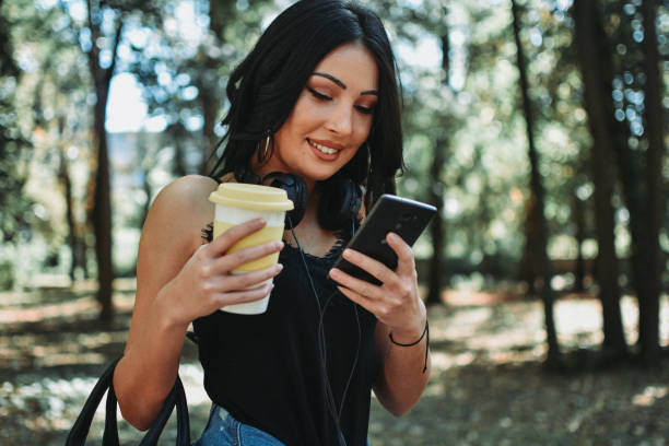 istock Woman texting and drinking coffee in the park 1177895582