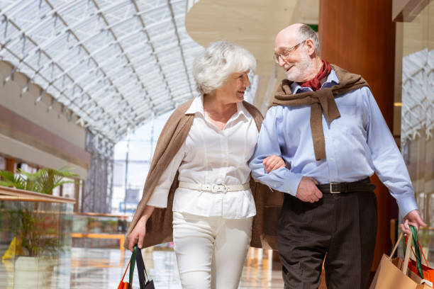 Senior couple with purchases Adult senior couple with purchases in bags at shopping mall mall walker stock pictures, royalty-free photos & images