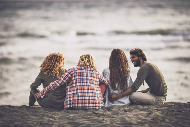 istock Rear view of happy couples communicating in sand on the beach. 1177897524