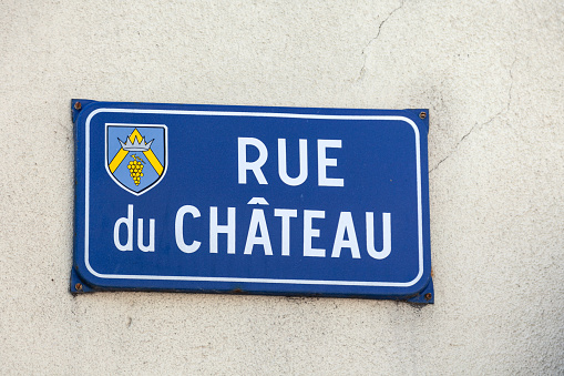 France Beaune 2019-06-20 Closeup authentic vintage steel or metal french street plate, french text - Rue de Chateau on old vintage wall. English translation: Castle Street