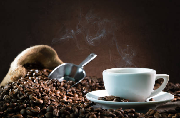 Cup of espresso with coffee beans Cup of espresso with coffee beans, bag, scoop and steam on dark background caffeine photos stock pictures, royalty-free photos & images