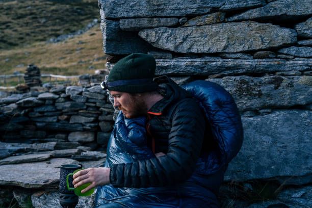istock Man in sleeping bag prepares to sleep in the mountains 1177903361