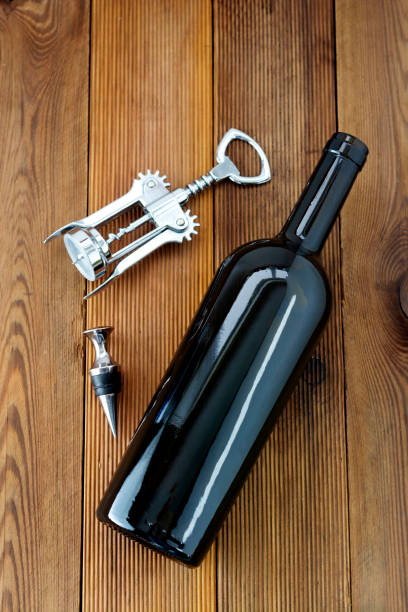 A bottle of wine with corckscrew, wooden rustic background. Flat lay wine drink with copy space for text.