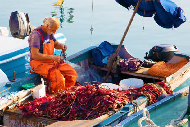 Fisherman at work on a boat in the old harbor of Ortygia