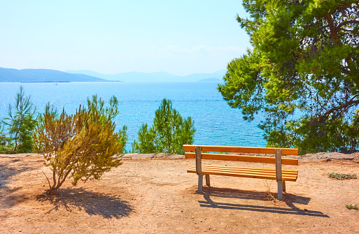 Small garden with bench on the coast in Aegina town on sunny summer day, Aegina Island, Greece - Landscape