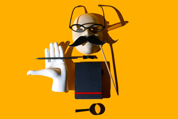 istock composition of various objects. Glasses, magnifying glass, pencil, mustache, butterfly, hand, notebook, mask. Form the image of a business person. Hard shadows on a yellow background 1177911820