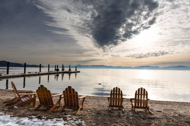Adirondack chairs on a beach at sunset