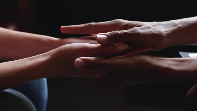 African woman holding hands of caucasian female, close up view