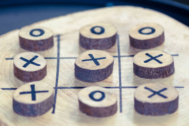 An incomplete game of tic tac toe with a pen on white paper