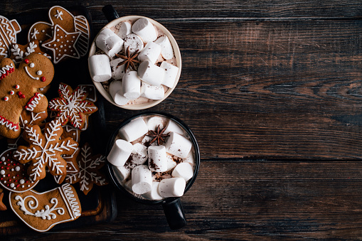 Christmas home atmosphere, cafe, celebration. Cozy and warming winter drink. Hot chocolate with melting marshmallows and homemade delightful festive sweets, copyspace